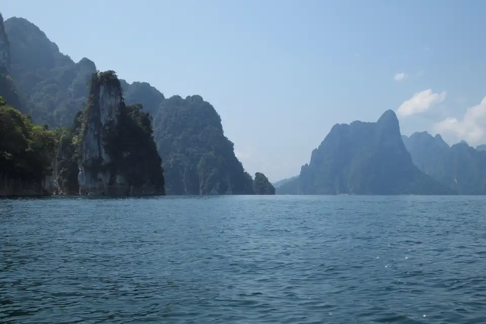 Limestone towers covered in forest rising straight out of a still reservoir at Khao Sok