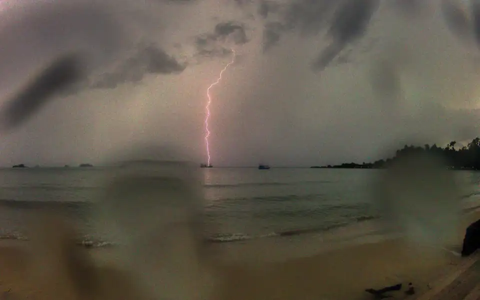 A lightning bolt striking the sea off a dark beach on Koh Chang during a thunderstorm