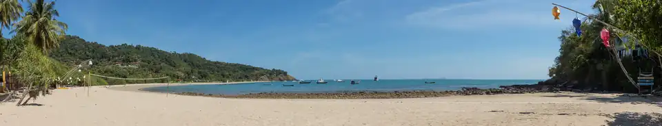 A wide empty horseshoe of sand at Kantiang Bay backed by steep forested hills, with a few long-tail boats offshore