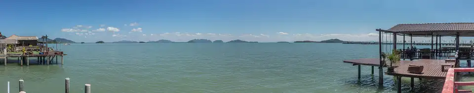 Wooden buildings on stilts standing out over green water at Lanta Old Town, with islands on the horizon