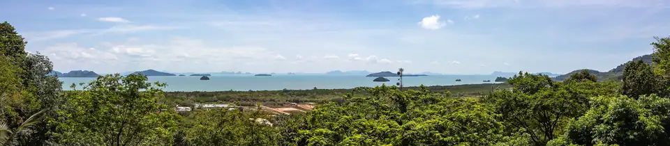 View east from a hill on Koh Lanta over forest and mangrove to a calm sea dotted with islands
