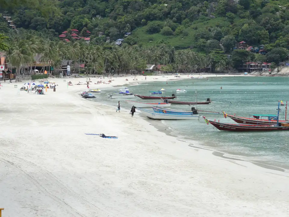 Haad Rin Sunrise Beach on Koh Phangan, a wide pale curve of sand with low buildings behind it