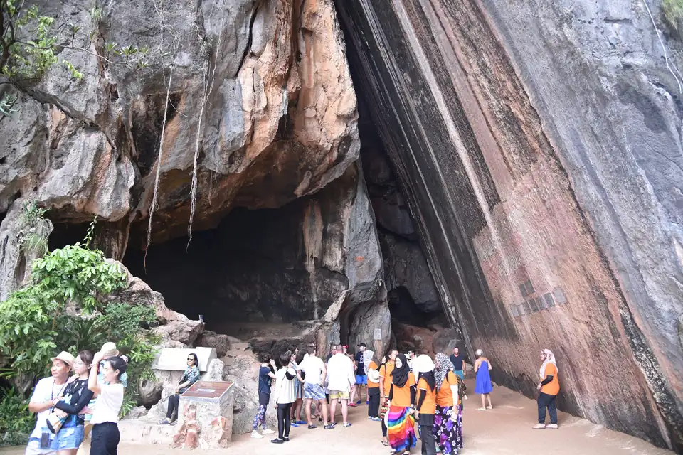 Visitors under the overhang and the leaning rock on Khao Phing Kan