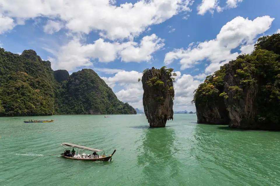 A longtail passing Ko Tapu, with Khao Phing Kan behind