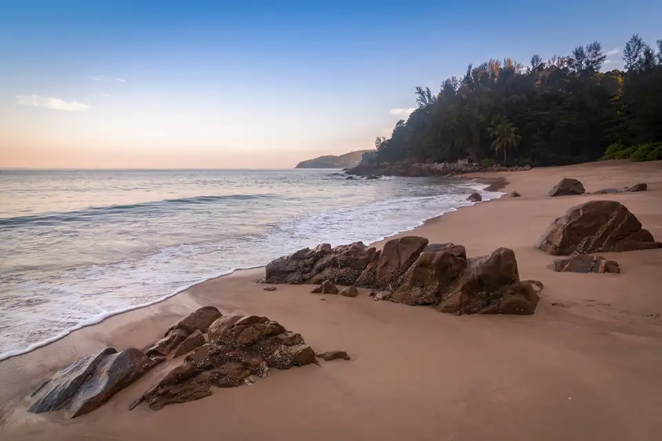 Rocks on the sand at Banana Beach with the headland behind