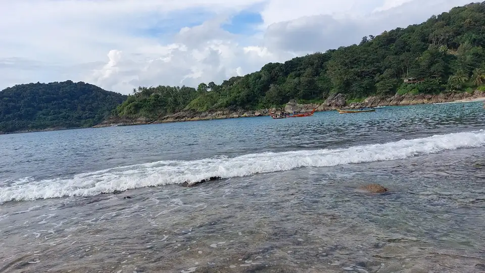 The rocky shallows at the end of Freedom Beach and the wooded shore across the bay
