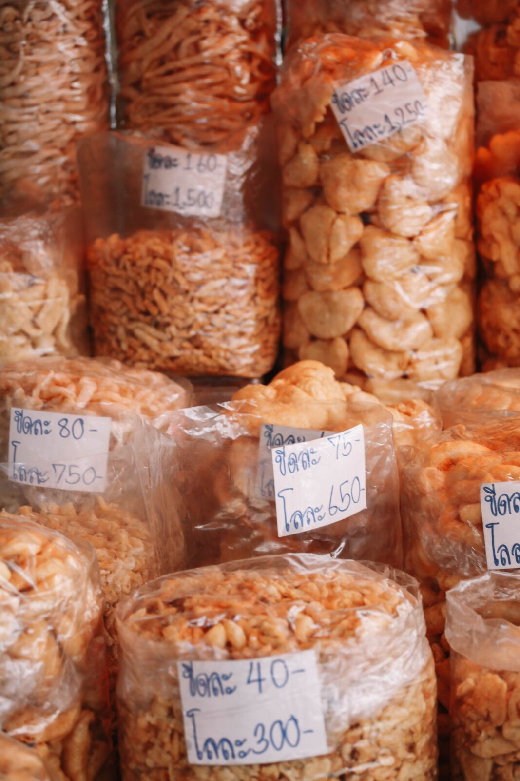 Bagged Thai snacks with handwritten prices at a Bangkok market